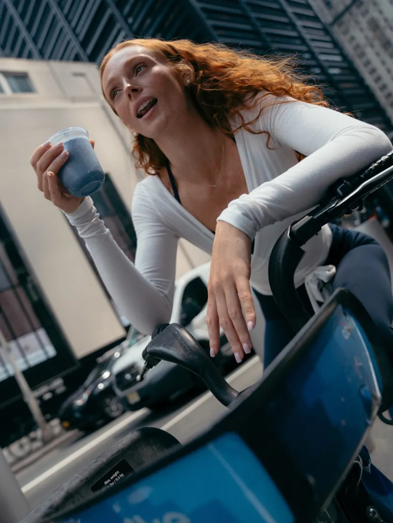 A rider on a Citi Bike holding a Blue Cloud Matcha